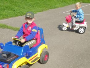 Děti vozící se v autíčku a motorce.