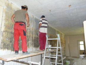 První patro obecního úřadu, dělníci odkrývající malby na zdech.