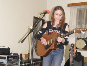 Zpěvačka hrající na kytaru.